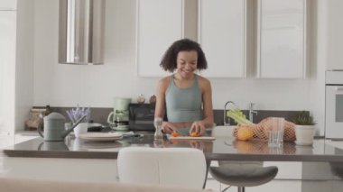 Parlak, ferah bir mutfakta yemek pişirirken dans eden neşeli melez kız.