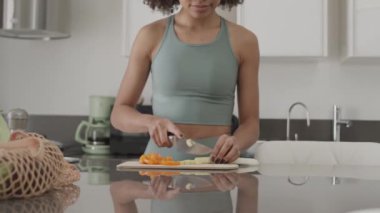 Dar etek giyen ve evde sağlıklı öğle yemeği hazırlarken taze sebze kesen formalı melez bir kız.