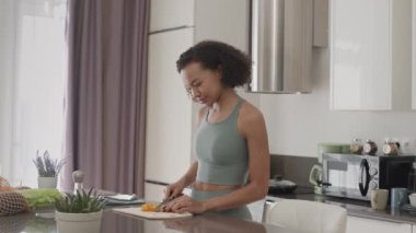 Evde kendine sağlıklı bir öğle yemeği hazırlayan iki ırklı genç kadının orta yavaşlığı.