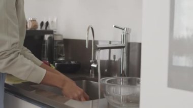 Mutfak lavabosunda taze meyve ve sebze yıkayan tanınmayan bir kadının orta bölüm yavaşlaması.