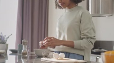 Işıl ışıl bir mutfakta çırpılmış yumurta pişiren melez genç ve güzel bir kadın.