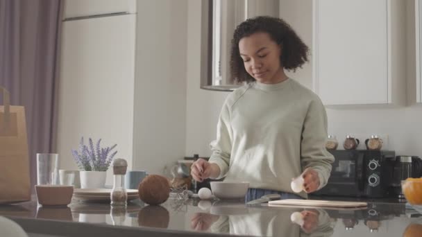 中低速の若いですブルネット産生女性作るスクランブルエッグのための朝食でミニマリストスタイルのキッチン — ストック動画