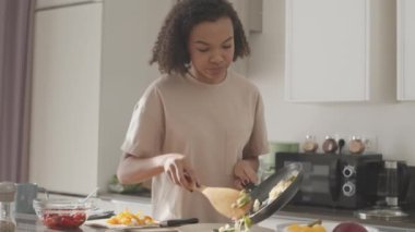 İç çamaşırlı, orta yavaş bir çift ırklı kadın tabakta sağlıklı kahvaltı servisi yapıyor, hafta sonunu evde geçiriyor.