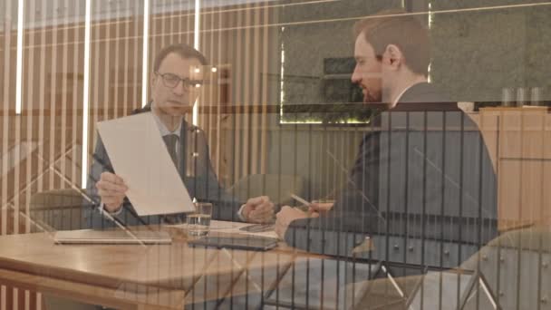 現代オフィスでの会議中にビジネス契約を議論する2つの成功した起業家のスローモをガラス窓の腰を介して — ストック動画