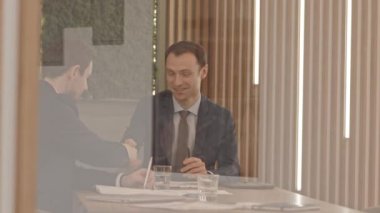 Camdan aşağı sarkan, iki kendine güvenen iş ortağının yavaş yavaş el sıkışması, toplantı masasında oturması.