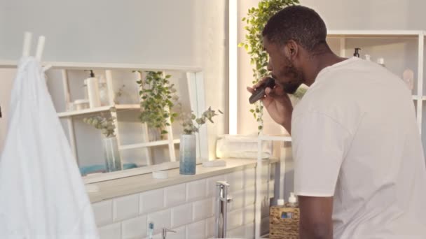 在现代的浴室里 英俊的黑人年轻人正在修整胡子和胡子 修整后的胡子站在镜子前 — 图库视频影像