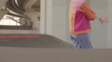 Pembe renkli blok ceketli, gözlüklü, otoparkta dans eden, plastikten yavaş beyaz bir kız.