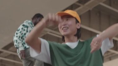 Enerjik Asyalı adam ve Afrikalı Amerikalı erkek arkadaşı hip hop dansı ve şantiyedeki serbest stil ile orta boy yakın çekim.