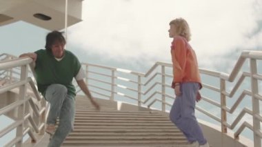 Yazın merdivenlerde dans eden renkli Y2K elbiseli genç Z jenerasyonunun tam boy yavaşlığı.