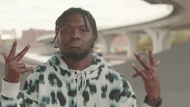 Hip hop dansı yaparken kameraya bakan gevşek Afrikalı Amerikalı adamın göğsü ağır ağır kaldırılsın.