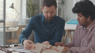 Tasarım projesinde birlikte çalışarak, ofiste yarattıkları ev modellemelerini inceleyen iki farklı mimarın belini yavaş yavaş kaldırın.