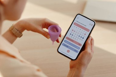 Mobil uygulama takvimi kullanarak adet döngüsü hesaplayan genç kadını kapat, boşluğu kopyala
