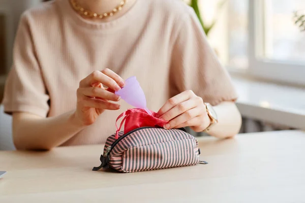 Stock image Closeup of young woman putting menstrual cup in cosmetic bag with other feminine essentials, copy space