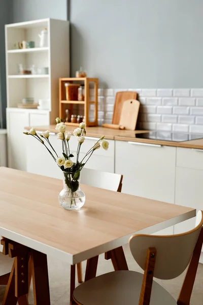 最小限のキッチンインテリアでのディナーテーブルの上の新鮮な白い花の垂直背景画像 コピースペース — ストック写真