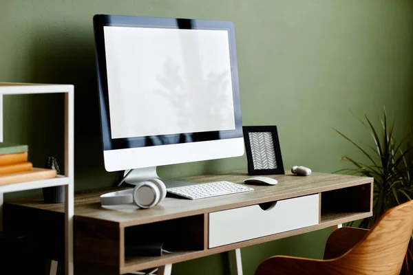 Background image of home office workplace with computer on wooden table against green wall, copy space