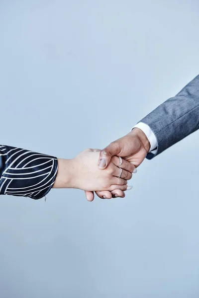 Minimal closeup of two business partners shaking hands against pale blue background, copy space