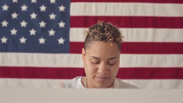 在准备投票的选区站在美国国旗前对着摄像机微笑的年轻伯利兹妇女的中特写画像 — 图库视频影像