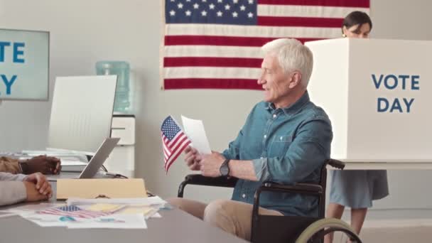 持乐观态度的白人老年人坐在轮椅上与当地投票站的工作人员交谈 慢吞吞地来到这里参加2022年美国总统选举的投票 — 图库视频影像