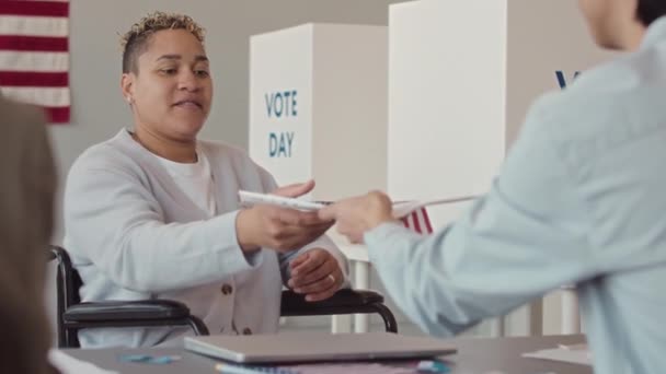 坐在轮椅上的年轻妇女在当地投票站登记投票的中速速度 — 图库视频影像