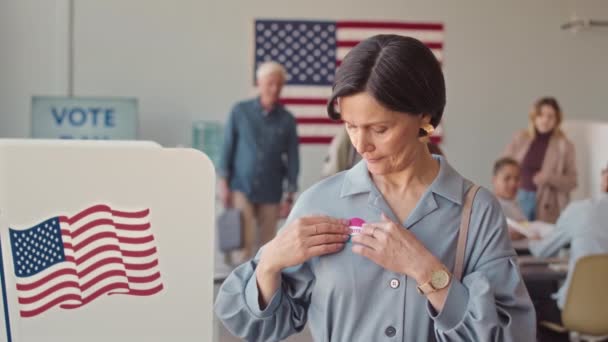 在当地投票站完成美国选举投票程序后 白色成年女性在胸前贴上 我投票 贴纸的中速肖像 — 图库视频影像