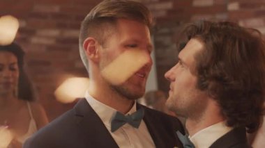 Smokinli, sevecen eşcinsel çiftin yavaş çekimleri. Birbirlerine bakıyorlar ve düğün partisinde dans ederken birbirlerine en yakın arkadaşlar maytap tutarken konuşuyorlar.