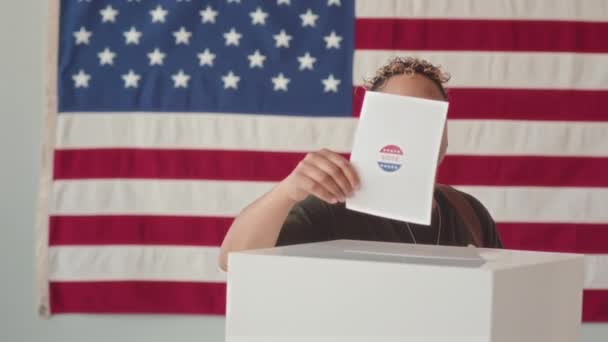 照片中年轻的比拉西亚女军人把选票放进投票箱 面对着靠墙上的美国国旗站着的摄像机微笑 — 图库视频影像