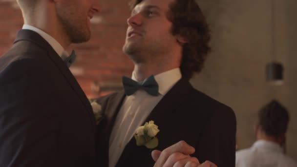 ティルトダウンSlowmoの愛情のあるゲイカップルで黒Tuxedos保持手と見つめながらダンス彼らの結婚式パーティー — ストック動画