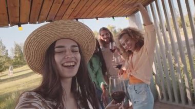Saman şapkalı güzel bir kızın el bilgisayarı yavaş yavaş kendini çok ırklı arkadaşlarıyla yazlık evde eğlenirken, sohbet ederken ve kırmızı şarap içerken videoya kaydediyor.