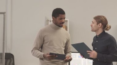 Ofiste yapılan görüşmenin ardından elinde dosya bulunan ve el sıkışan iki genç ve kendine güvenen iş adamının yavaşlığını azalt.