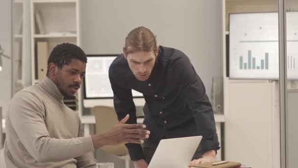 Lentidão Média Dois Colegas Masculinos Multiétnicos Usando Laptop Enquanto Trabalham — Vídeo de Stock