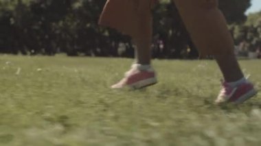 Aydınlık bir günde yeşil karahindiba tarlasında koşan tanınmayan küçük kızın yavaş yavaş izini sürüyorum.