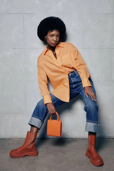 오렌지색 톤으로 콘크리트 배경에 대항하여 유행하는 패션을 여성의 — 스톡 사진