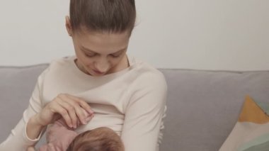 Waist up slowmo of young loving mother breastfeeding her newborn baby holding her tight in her arms