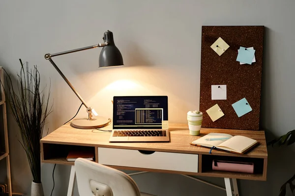 ランプライト付きノートパソコン画面上のコードと居心地の良いホームオフィスの職場の背景画像 コピースペース — ストック写真