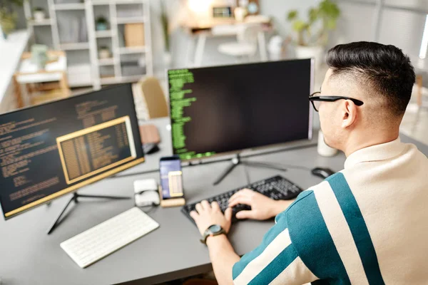 사무실 내부에서 일하는 컴퓨터 스크린에서 프로그래밍 코드로 키보드로 타이핑하는 아시아인 — 스톡 사진