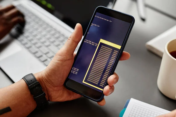 Stock image Close up of male IT developer holding smartphone with code on screen, copy space