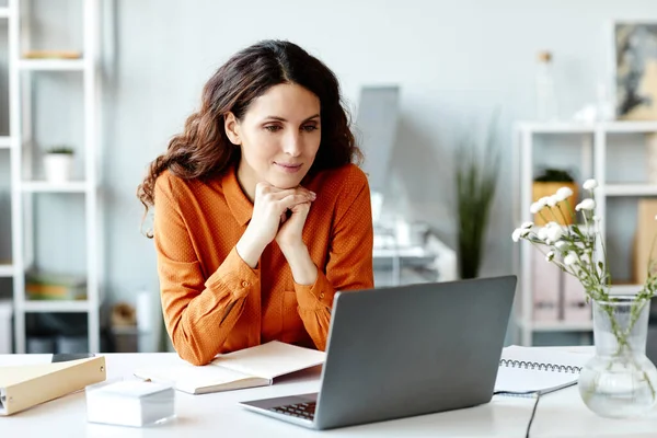 現代のオフィスの机に座っている女性マネージャーの水平ノートパソコンでインターネットで何かを見て — ストック写真
