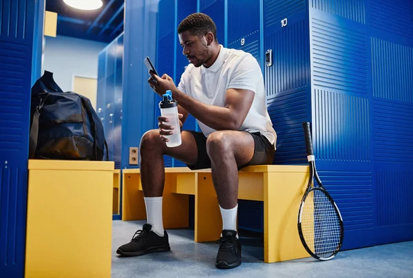 테니스 룸에서 스마트폰을 사용하는 근육질 스포츠맨의 장사진 — 스톡 사진