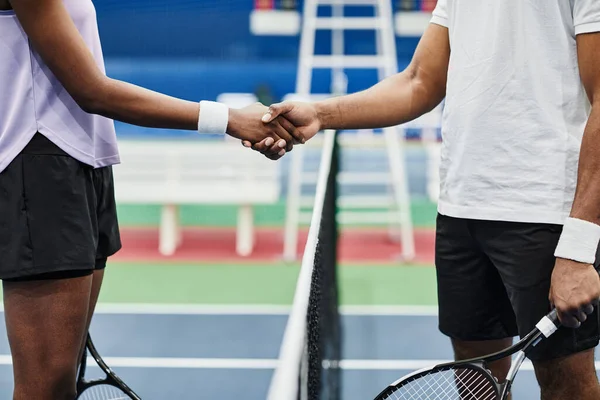 屋内コートで試合中にネット上で握手をする2人のテニス選手のサイドビュー — ストック写真