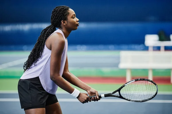 屋内コートでテニスをしている若い黒人スポーツ女性のサイドビューの肖像画 コピースペース — ストック写真