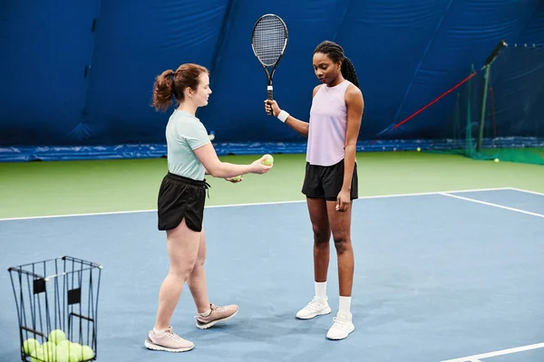 室内训练中与年轻黑人女子一起工作的女子网球教练的全长肖像 — 图库照片