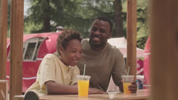 Neşeli Siyahi Bir Adam Yaşındaki Oğlu Parkta Bir Kafede Oturmuş — Stok video