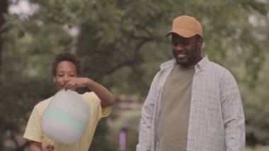 Afrika kökenli Amerikalı baba ve 12 yaşındaki oğlu yazın parkta yürüyüp pamuk helva yiyor ve sohbet ediyorlardı.