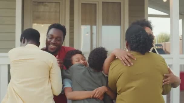 两只快乐的非洲裔美国夫妇和11岁至12岁的孩子在前廊相遇 互相问候和拥抱的中景照片 — 图库视频影像