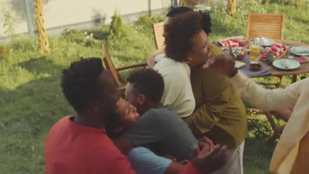 上图拍摄的是两个快乐的非洲裔美国家庭 他们带着年幼的孩子在后院的绿色草坪上聚会 在温暖的阳光明媚的日子里在户外与朋友们共进晚餐 — 图库视频影像