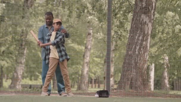 全长拍摄的非裔美国人教他12岁的儿子在夏天室外练习棒球时击球 — 图库视频影像