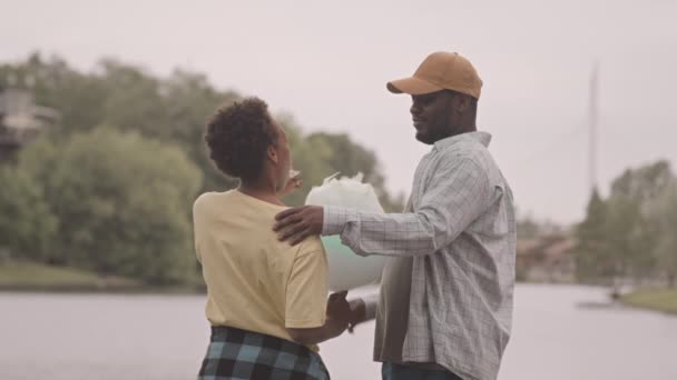 アフリカ系アメリカ人の男性と12歳の息子のリアビュー中遅いスローモーと 川に立って話し 自然と時間を楽しむコットンキャンディー — ストック動画