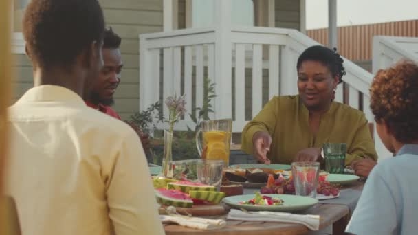暖かい晴れた日の家の庭で昼食をしながら 大きな幸せなアフリカ系アメリカ人の家族のチャットと話し合いのニュースを待ちます — ストック動画