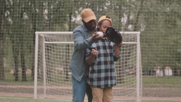 中等速度的非裔美国人教育他12岁的儿子去打棒球 夏天在公园里进行户外运动 — 图库视频影像