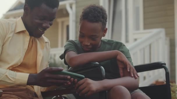 아프리카계 미국인 휠체어 형제와 스마트 폰에서 게임을 여름에 — 비디오